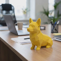 Cute low poly Corgi 3D printed desk toy figurine sitting on a modern office desk with laptop in background. Geometric style decor.